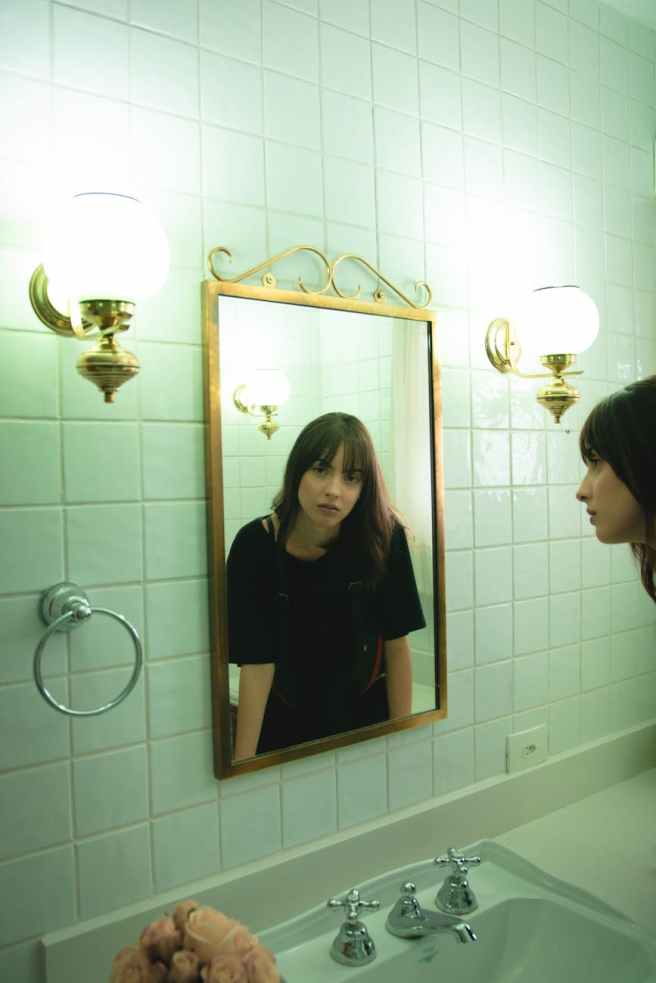 woman in black t shirt staring on wall mirror