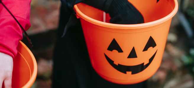 kids putting treats in bucket on Halloween