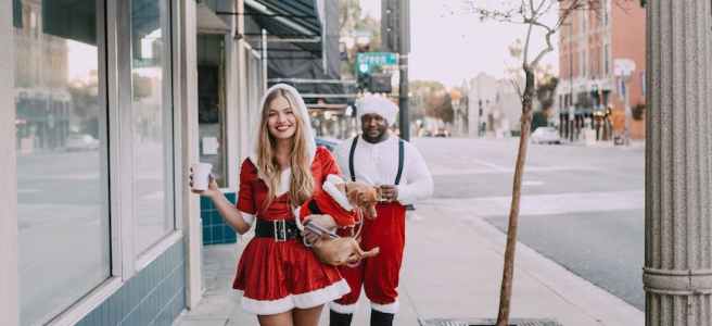 a man and a woman in santa costume walking on sidewalk