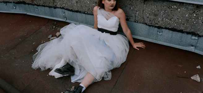 woman in white dress and black boots sitting on a concrete floor