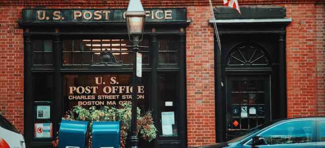a view of a u s post office in a red brick storefront building from across the road