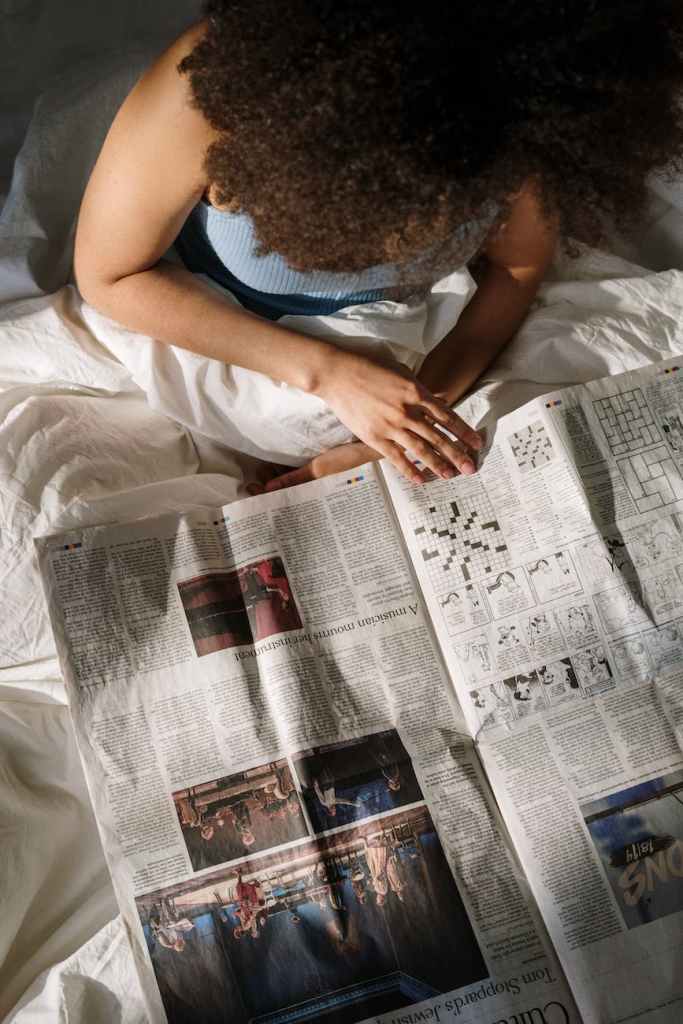 woman lying in bed reading the newspaper